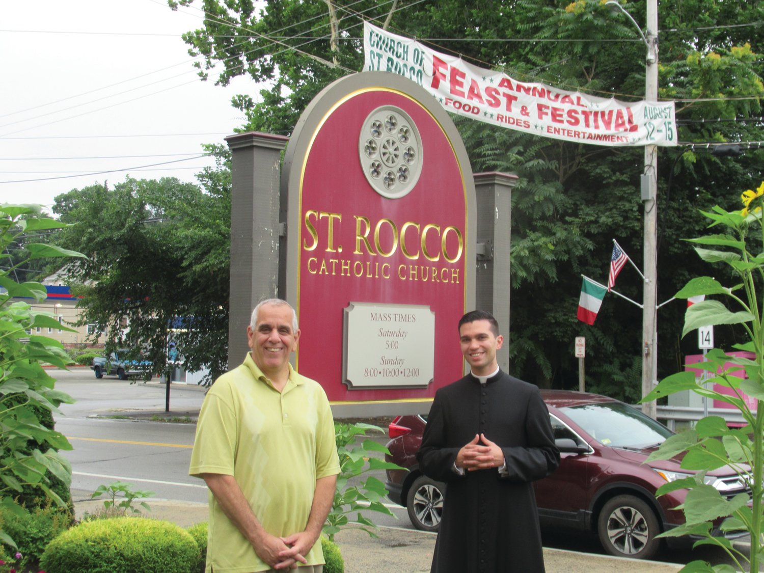 DIVINE DUTY: Richard Montella (left), long-serving co-chairman of the now 81-year-old Saint Rocco’s Fest and Festival, is joined by Seminarian Stephan Coutcher outside the Roman Catholic Church conveniently located on the corner of Plainfield Pike and Atwood Avenue in Johnston.